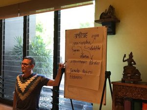 Richard teaching yoga philosophy with Sanskrit and English terms on a whiteboard.